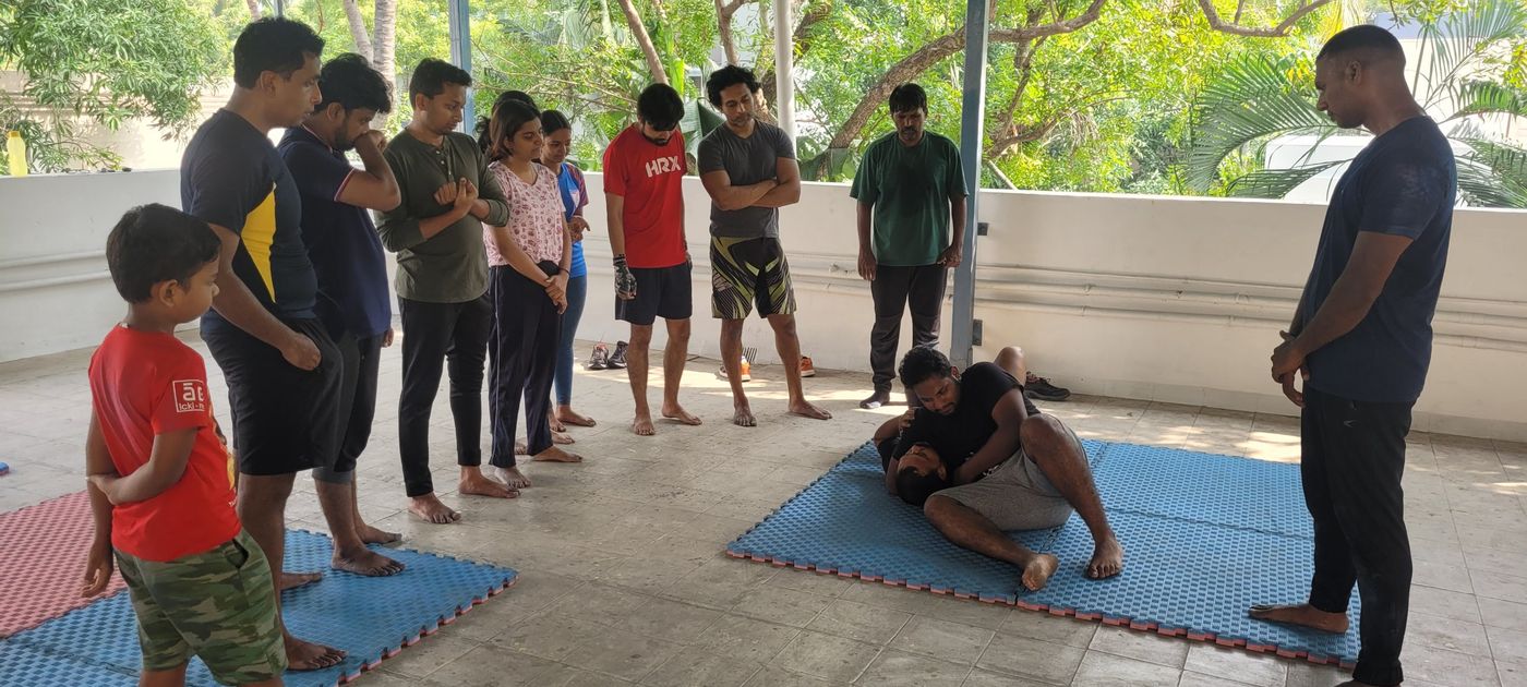 Krav Maga class participants watching a ground technique demonstration on mats at a weekend class