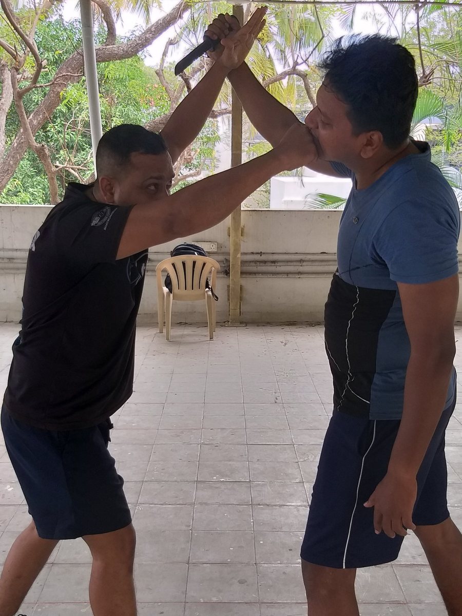 Krav Maga knife defence drill: one partner blocks an overhead attack with a training knife and strikes