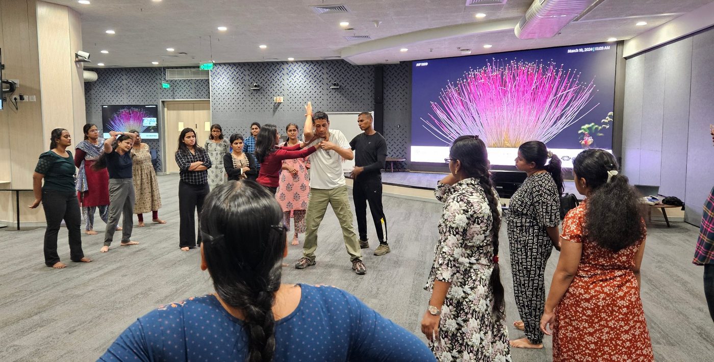 An instructor demonstrates a defence against a neck hold to a group of women employees at a corporate workshop